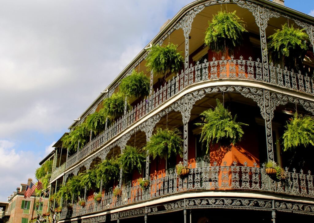 New Orleans Vows | Wedding Officiant in New Orleans Detailed view of ornate ironwork balconies with lush greenery in New Orleans under a vibrant sky.